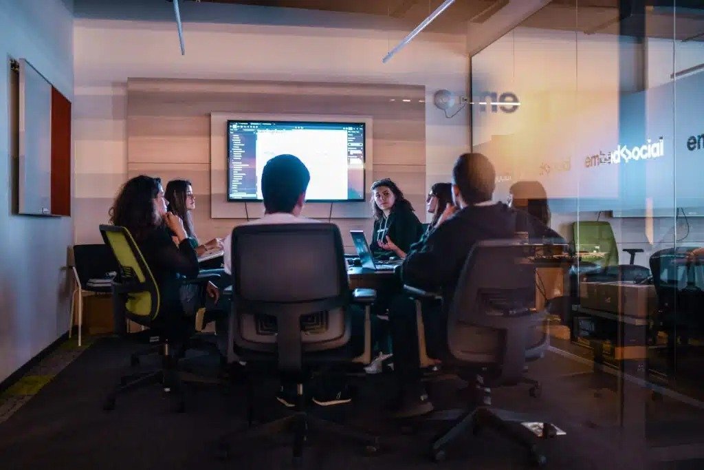 A diverse group of individuals engaged in discussion around a conference table in a professional setting.